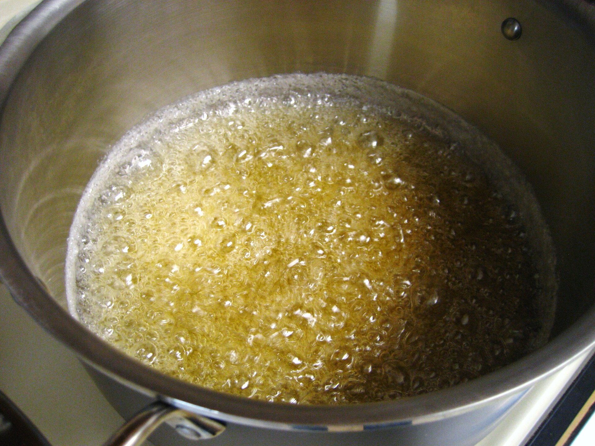 Na fotografii zaprezentowano patelnię, na której, pod wpływem temperatury, cukier zmienia swój stan skupienia ze stałego w ciekły (karmel). Żółtobrązowa, bulgocząca, gęsta ciecz.