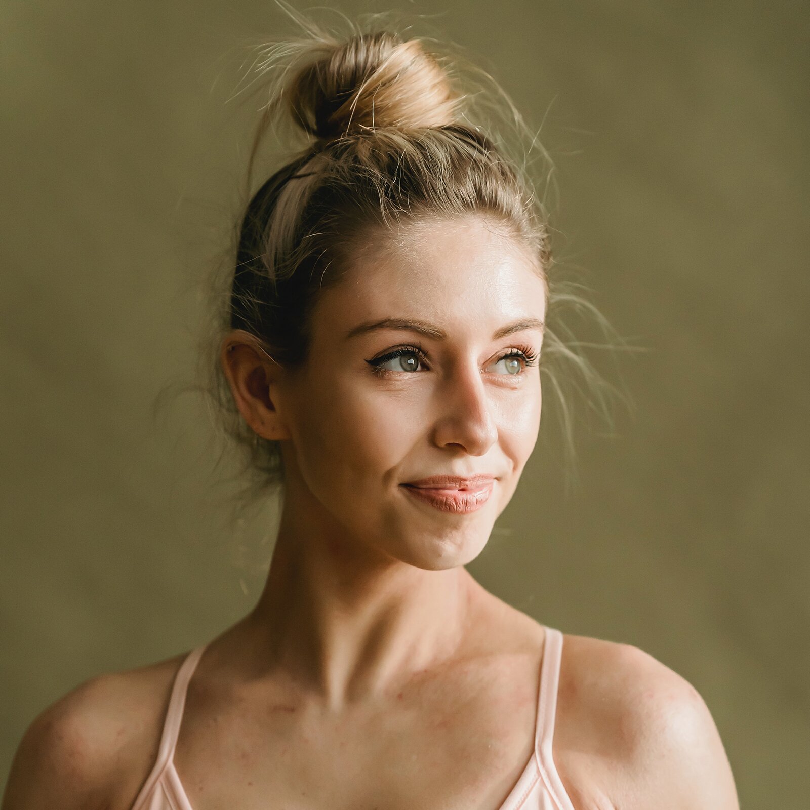 Zdjęcie przedstawia młodą, szczupłą kobietę. Ma blond włosy, szare oczy i długie rzęsy. Włosy ma upięte w koka.