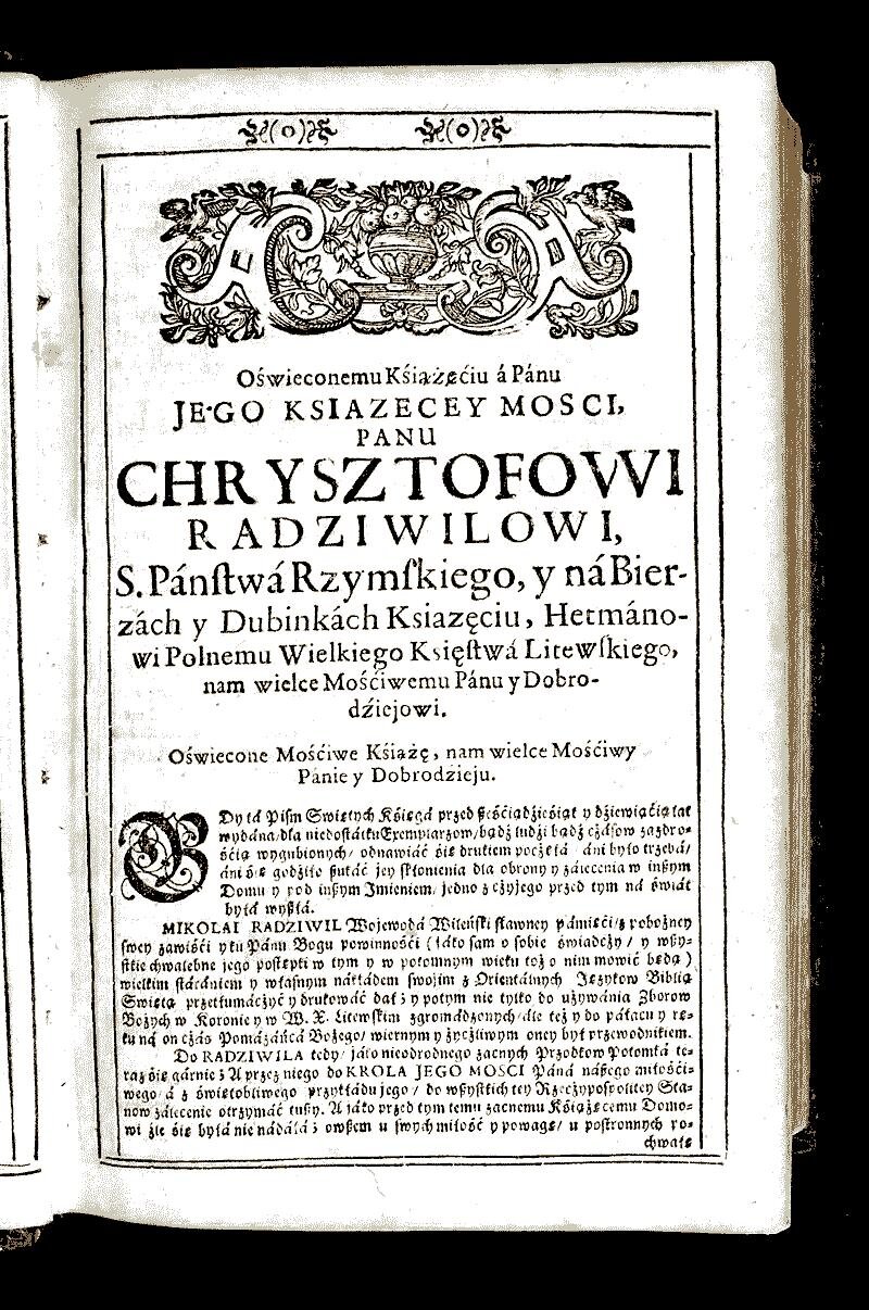 Ilustracja przedstawia kopię karty starej książki. Strona jest obramowana prostymi podwójnymi liniami. Na samej górze, pomiędzy dwiema liniami, widnieją dwa małe ornamenty. Większość strony zajmują napisy. Nad nimi umieszczony jest rysunek składający się z pucharu z owocami, w centrum otoczonego liśćmi i ornamentami; po obu jego stronach znajdują się rysunki ptaków z uniesionymi skrzydłami. Napis na karcie: "Oświeconemu Kśiążęćiu á Pánu JEGO KSIAZECEY MOSCI, PANU CHRYSZTOFOWI RADZIWILOWI, S. Páńſtwá Rzymſkiego, y ná Bier‑zách y Dubinkách Ksiazęciu, Hetmáno‑wi Polnemu Wielkiego Księſtwá Litewſkiego, nam wielce Mośćiwemu Pánu y Dobro‑dźiejowi. Oświecone Mośćiwe Kśiążę, nam wielce Mościwy Pánie y Dobrodźieju. Pierwsza litera dalszej części tekstu jest ozdobna w ornamenty i większa. Gdy tá Piſm Swiętych Kśięgá przed ßeśćiądzieśiąt y dźiewiąćią lat wydána, dla niedoſtátku Exemplarzom, bądź ludźi bądź cżáſow zazdrośćią wygubionych, odnawiáć śię drukiem pocżęłá, áni było trzebá, áni śię godziło ßukáć jey skłonienia dla obrony y zálecenia w inßym Domu y pod inßym Imieniem, jedno z czyjego przed tym ná świat była wyßłá. MIKOLAI RADZIWIL Wojewodá Wileńſki ſławney pámięci, z pobożney ſwey zawiśći y tu Pánu Bogu powinnośći (jáko ſam o ſobie świadczy, y wßystkie chwalebne jego poſtępki w tym y w potomnym wieku toż o nim mowić będą) wielkim ſtárániem y właſnym nákłádem ſwojim z Orientálnych Językow Biblią Swiętą przetłumácżyć y drukowáć dał; y potym nie tylko do używánia Zborow Bożych w Koronie y w W. X. Litewſkim zgromádzonych, ále też y do páłacu y ręku ná on cżás Pomázáńcá Bożego, wiernym y życzliwym oney był przewodnikiem. Do RADZIWILA tedy, jáko nieodrodnego zacnych Przodkow Potomká teraz śię gárnie; A przez niego do KROLA JEGO MOSCI Páná náßego miłościwego á z świętobliwego przykłádu jego, do wßystkich tey Rzecżypospolitey Stanow zálecenie otrzymać tußy. A jáko przed tym temu zacnemu Kśiążęcemu Domowi źle śię byłá nie nádáłá; owßem u ſwych miłość y powagę, u poſtronnych pochwałę".