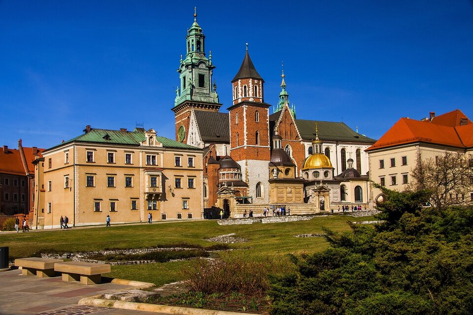 Zdjęcie przedstawia Katedrę na Wawelu, z przylegającą do niej Kaplicą zbudowaną z trzech części o podobnej wysokości. Wzniesioną na planie kwadratu. Znajduje się w niej ośmioboczny bęben. W jego ścianach znajdują się okrągłe okna. Od góry kaplicę pokrywa złota kopuła. Najwyższą partię budowli stanowi smukła latarnia zwieńczona krzyżem. Każda z kondygnacji kaplicy jest ozdobiona dekoracją, nawiązującą do motywów antycznych.