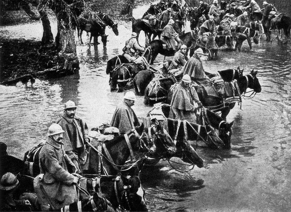 Zdjęcie przedstawia wojska francuskie. Wszyscy siedzą na koniach. Są ubrani w płaszcze oraz hełmy. Brną przez wodę.