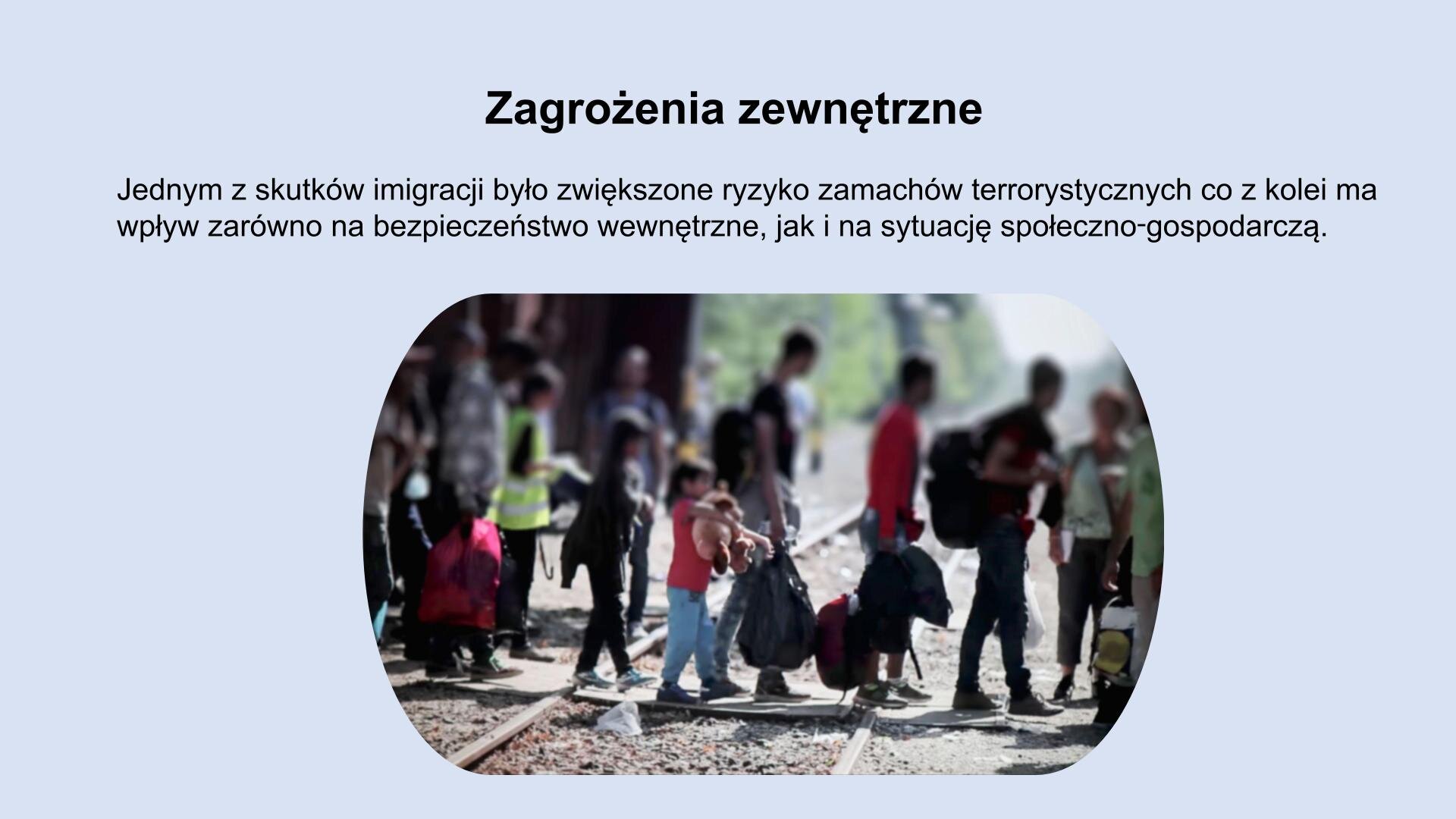Jasnoniebieski slajd. W górnej części slajdu tekst: „Zagrożenia zewnętrzne. Jednym ze skutków imigracji było zwiększone ryzyko zamachów terrorystycznych, co z kolei ma zwrotny wpływ zarówno na bezpieczeństwo wewnętrzne, jak i na sytuację społeczno‑gospodarczą”. U dołu slajdu zdjęcie przedstawiającą grupę dorosłych i dzieci, którzy przechodzą przez tory. Wszyscy trzymają w rękawch bagaże.