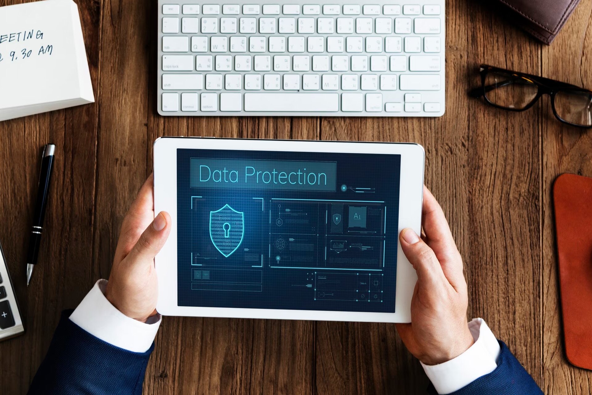 Zdjęcie przedstawia dłonie trzymające tablet, na którym wyświetla się napis w języku angielskim: DATA PROTECTION.