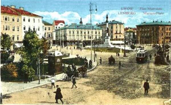 Pocztówka w technikolorze przedstawia plac Mariacki we Lwowie w 1915 roku. Dookoła placu stoją dwu i jednopiętrowe kamienice. Przez plac biegnie linia tramwajowa, po której jedzie tramwaj. Po placu spacerują ludzie, jeżdżą dorożki. W lewym dolnym rogu widać mały skwer z niewielkimi drzewami. Na środku placu stoi pomnik. Postać umieszczona jest na białej, wysokiej kolumnie. W prawym górnym rogu napis w dwóch językach, polskim i niemieckim: Lwów. Lemberg. Plac Mariacki.  Marlen Platz