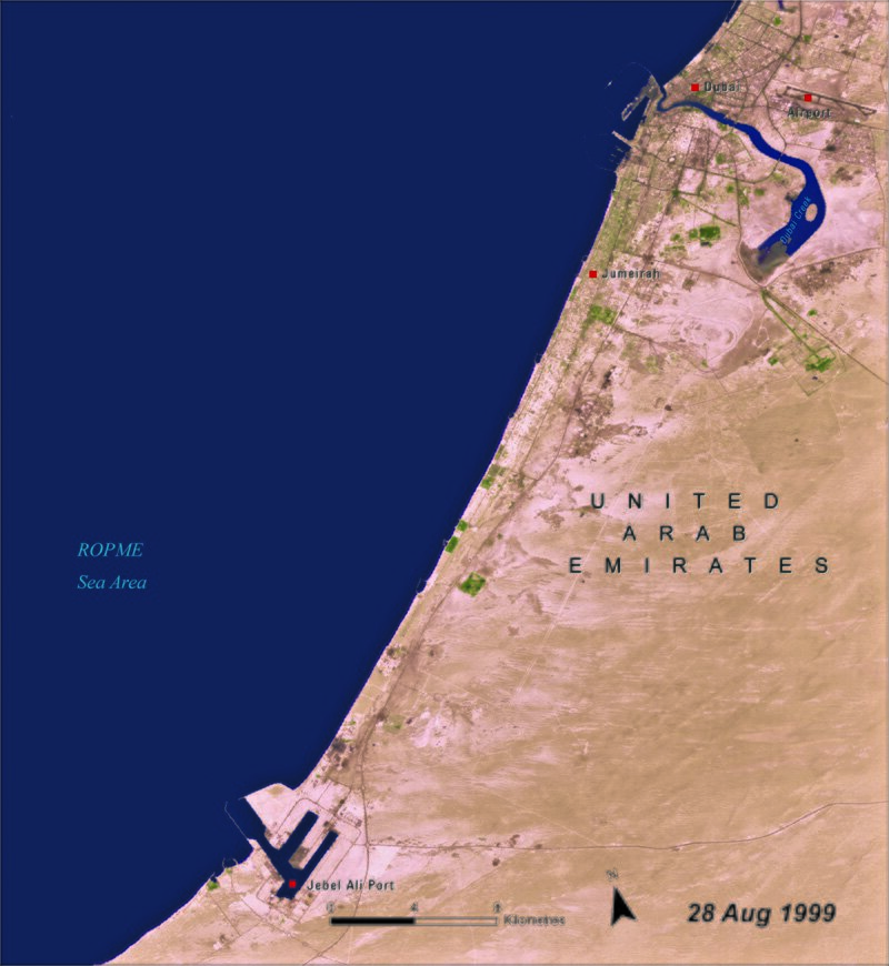 Na fotografii z 1999 roku widać wybrzeże Zjednoczonych Emiratów Arabskich we fragmencie, w którym znajduje się Dubaj. Zatoka Perska ma kolor ciemnoniebieski. Wybrzeże w większości jest pustynne, z niewielkimi zielonymi plamami symbolizującymi roślinność. W ląd w górze obrazka wrzyna się zatoka, na dole widać zarys portu. 
