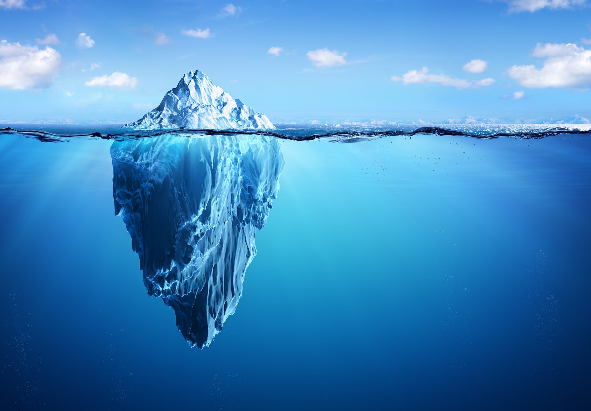 Rys. a. Ilustracja pokazuje górę lodową zanurzoną w morzu. Widoczna jest cała część podwodna, która jest znacznie większa niż część znajdująca się nad powierzchnią wody. 