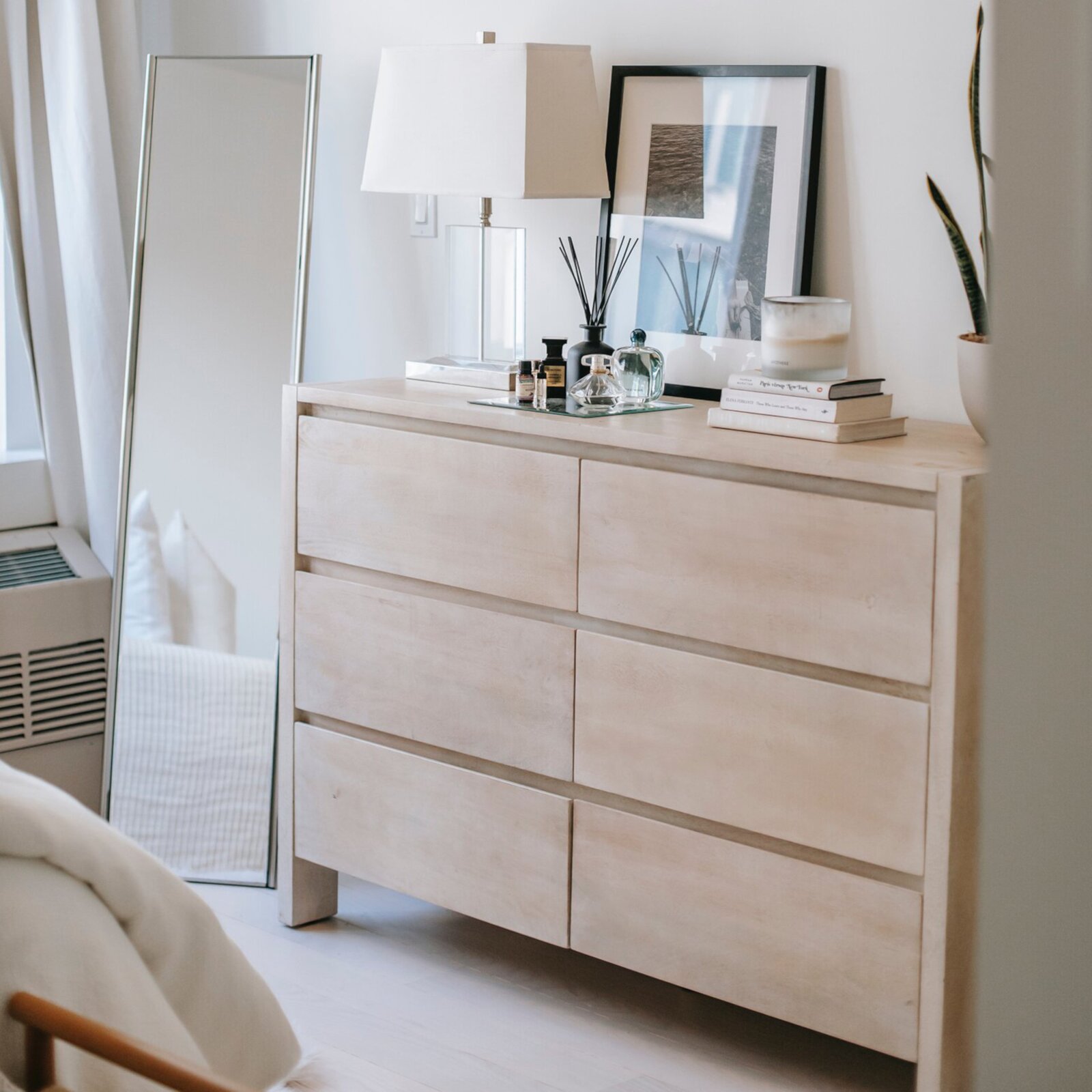 Ilustracja przedstawia pokój w którym stoi komoda. Komoda jest w jasnym kolorze, posiada trzy szuflady. 