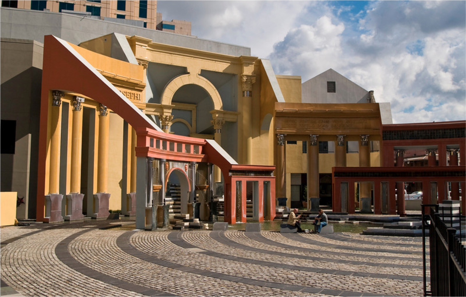 Ilustracja w kształcie prostokąta przedstawia Piazza d’Italia projektu Charlesa Moore'a. Ukazuje zespół architektoniczny, nawiązujący do antyku. Część wschodnia zawiera architektoniczne odniesienia do Forum Romanum: stiukowe i żywe kolory kolumnady w kolorach żółtym, ochry i czerwieni reprezentują pięć klasycznych porządków. Łukowate drzwi zapewniają dostęp do zagłębionej sceny otoczonej ścianami ozdobionymi łacińskim pismem i twarzą Moore'a na podwójnych kartuszach. Kaskadowa Fontanna Św. Józefa nawiązuje do formy włoskiej. W tle na zdjęciu widoczne są inne budowle.