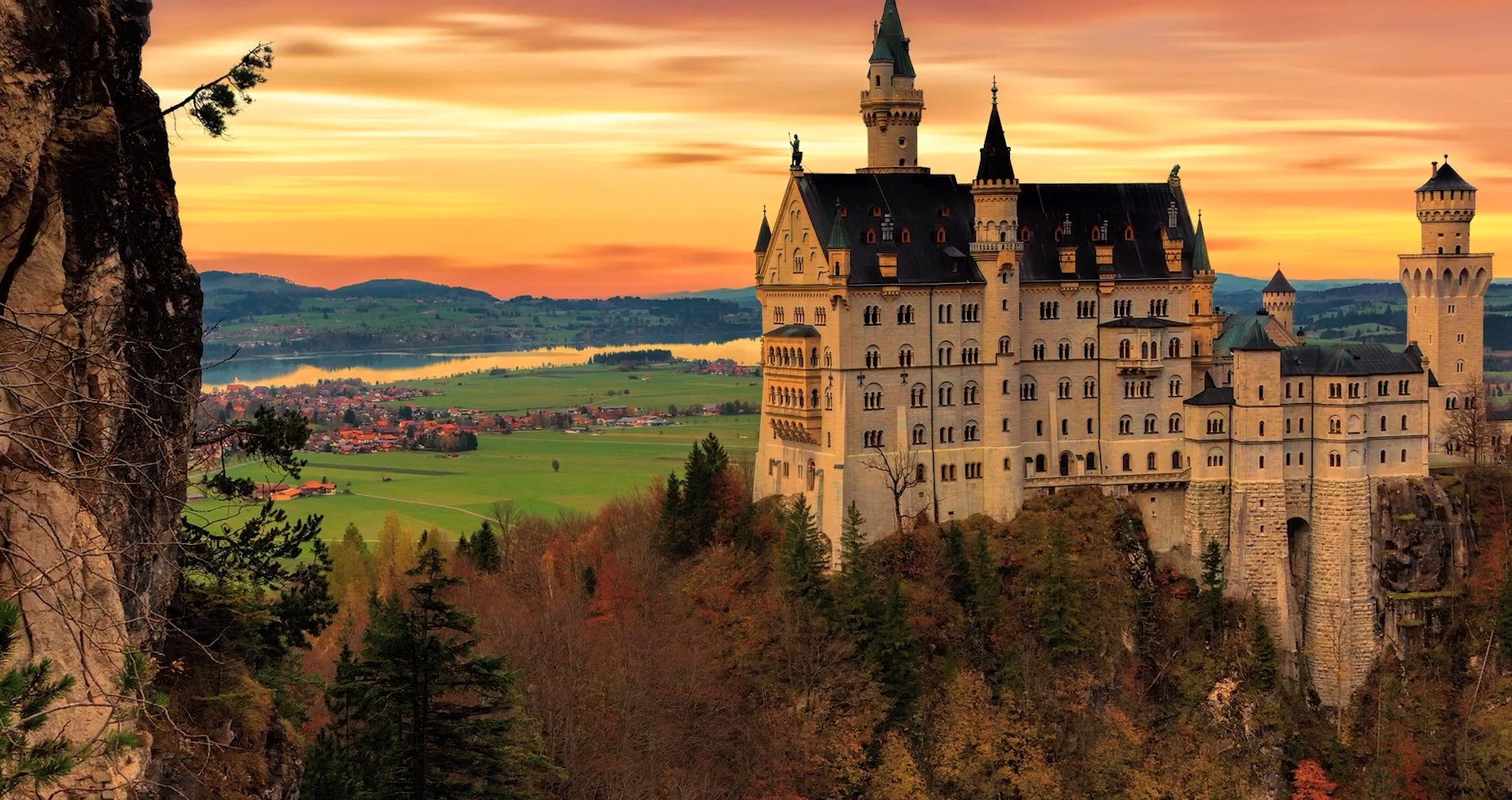 Ilustracja prezentuje majestatyczny zamek, wyróżniający się swoją imponującą architekturą. Zbudowany z kamienia, posiada wieże, baszty i zdobienia, które nadają mu charakterystyczny średniowieczny urok. Otoczony malowniczym krajobrazem górskim.