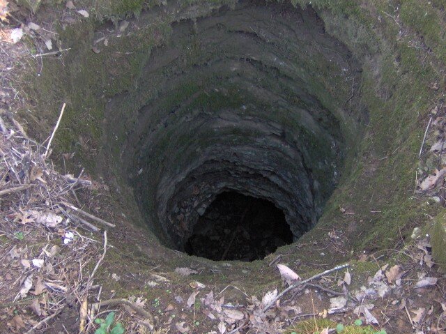 Zdjęcie przedstawia studnię krasową. Jest to otwór w ziemi w kształcie okręgu.