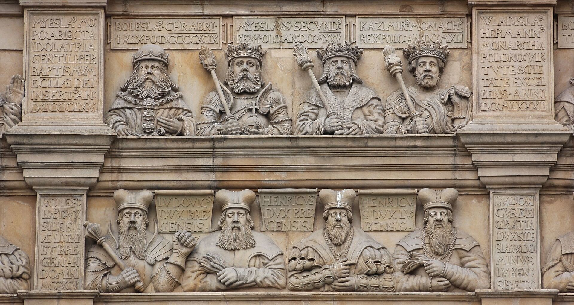 Ilustracja przedstawia płaskorzeźbę ścienną. Widocznych jest osiem postaci, prawdopodobnie królów. Obok każdego znajdują się tablice z wybitymi w kamieniu napisami.