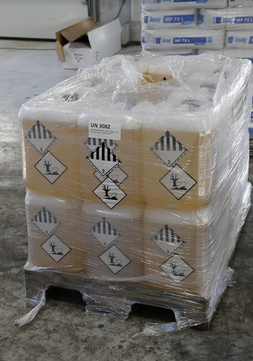 Grafika przedstawia, kanistry z cieczą na palecie. Na kanistrach widnieją dwa oznakowania
Pierwsze od góry to oznaczenie to czarno biały romb o podwójnym czarnym konturze. Zewnętrzny narysowany jest linią przerywaną, wewnętrzny ciągłą. Górna połowa rombu zamalowana jest w pionowe czarne i białe pasy o równej szerokości. W dolnym rogu podkreślona czarna dziewiątka.
Drugie  oznakowanie to biały romb z czarną obwódką w środku znajduje się martwe drzewo bez liści i ryba leżąca na grzbiecie, mająca otwarty pyszczek. 

