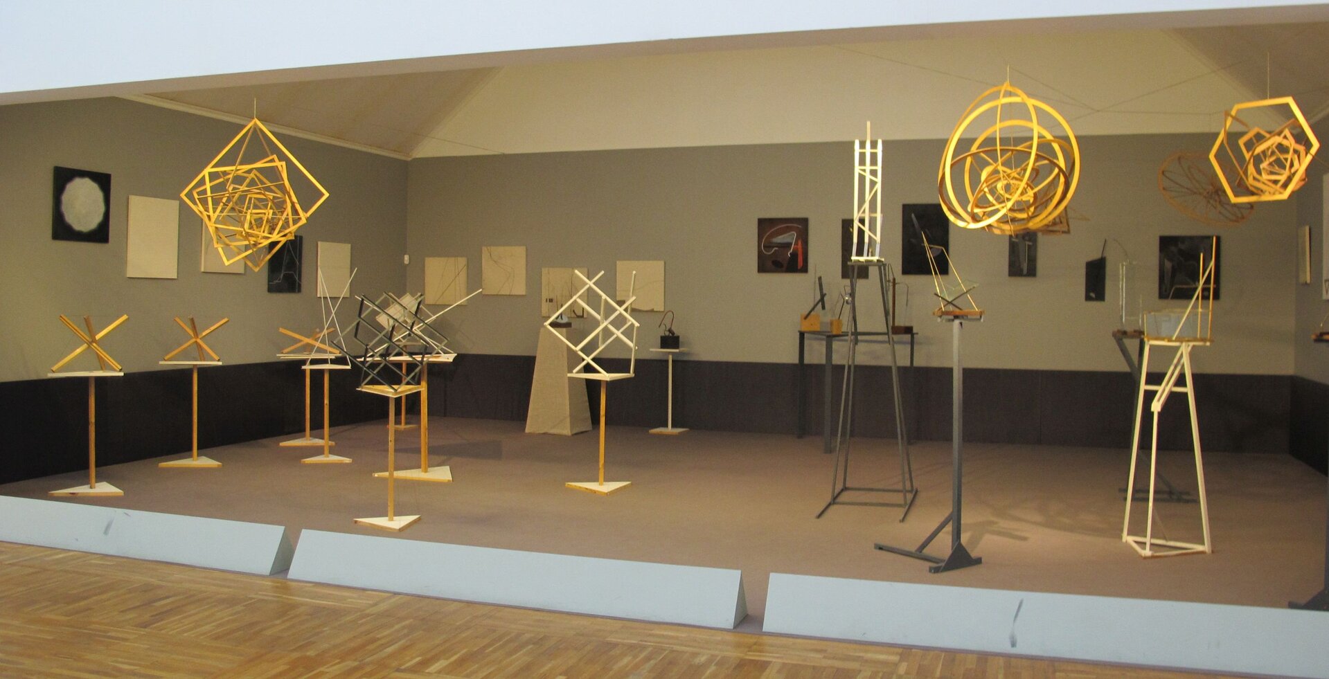 Instalacja rekonstrukcji wystawy „5x5 = 25” z 1921 r .Zdjęcie ukazuje wystawę, na podłodze umieszczone są wysokie stojaki na których umieszczono różne figury, figury zwisają także na nitkach z sufitu.