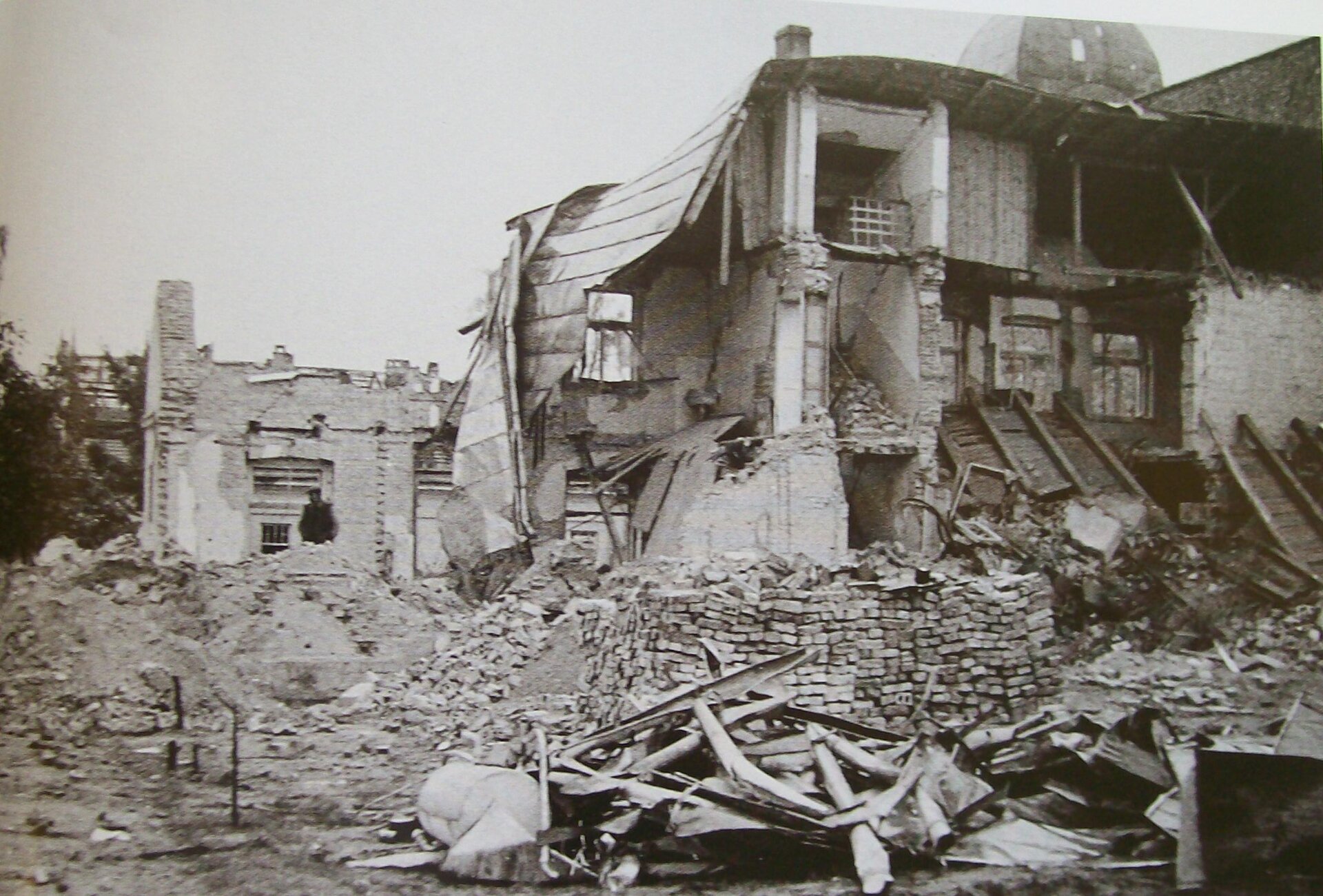 Zdjęcie przedstawia zbombardowane domy mieszkalne w centrum Wielunia. Na gruzowisku widać deski, cegły.