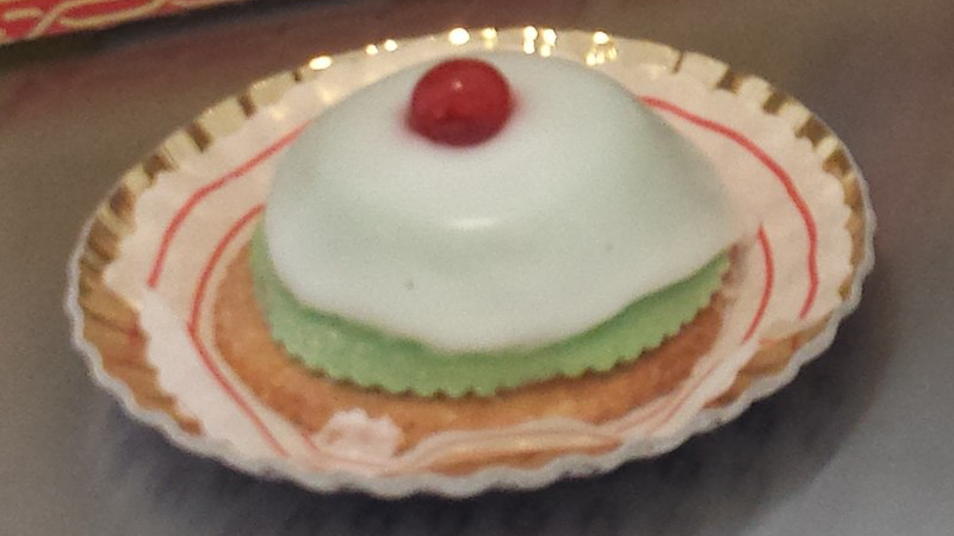 Zdjęcie przedstawia biszkoptowe włoskie ciastko Cassata siciliana wykończone grubą warstwą lukru i wisienką na górze.