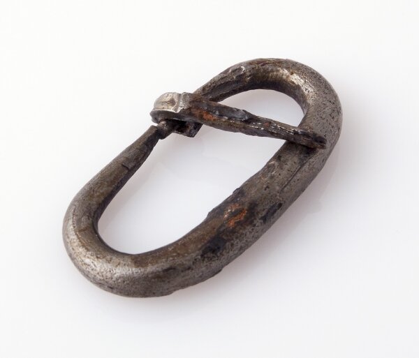 Ilustracja przedstawia sprzączkę żelazną do pasa. Ma ona eliptyczny kształt, a przez jej górną cześć przebiega zapięcie. 