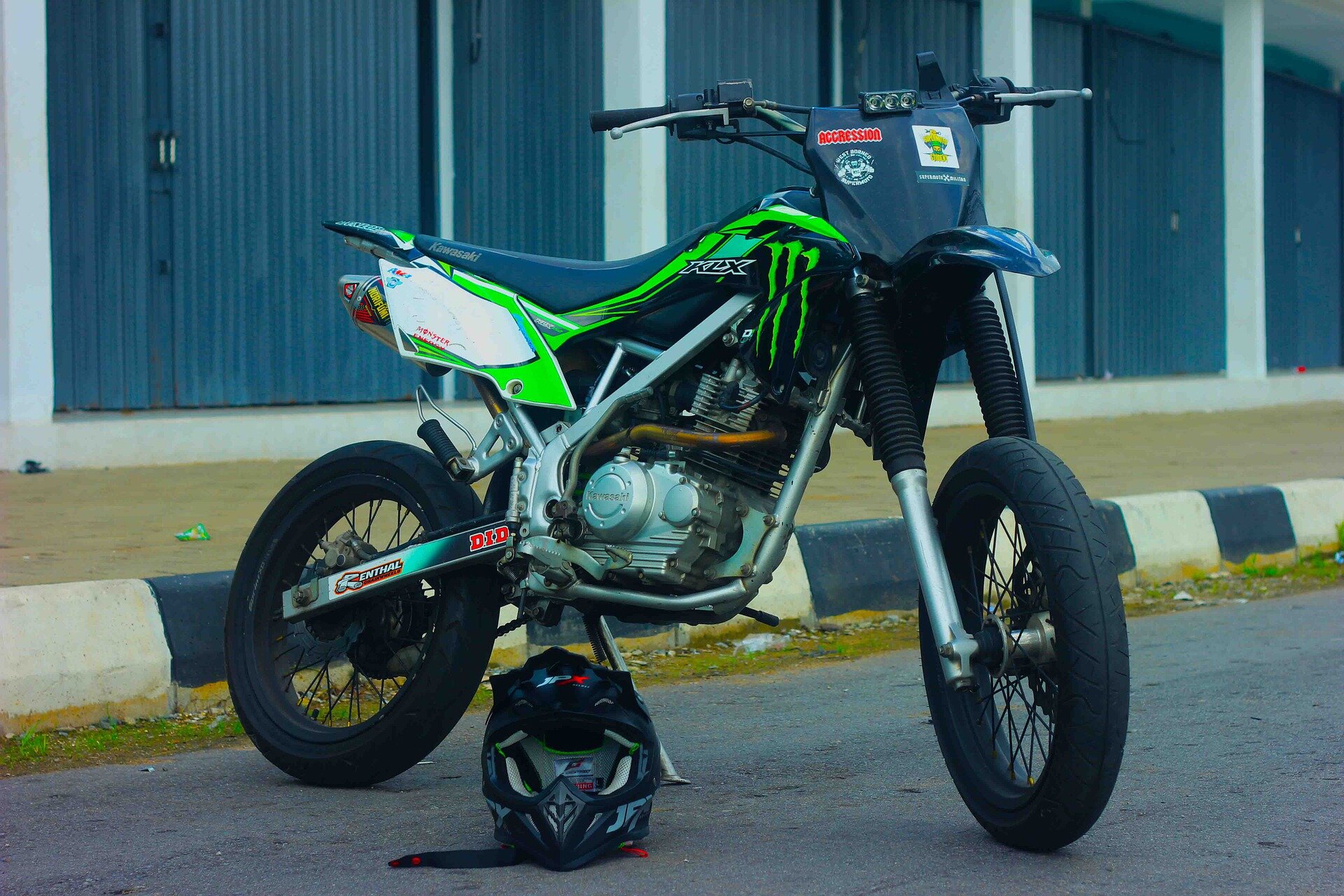 Zdjęcie przedstawia motocykl o lekkiej konstrukcji. Opony średniej grubości, brak osłon aerodynamicznych, brak przedniej szyby. Przy motocyklu leży kask. 