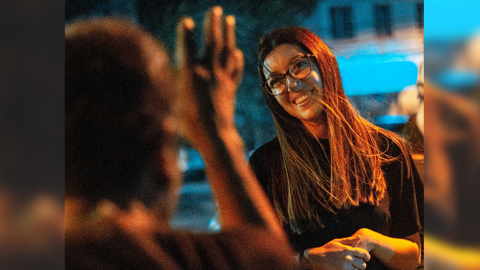 Zdjęcie przedstawia młodą, uśmiechniętą kobietę. Ma długie, proste włosy i nosi okulary. 