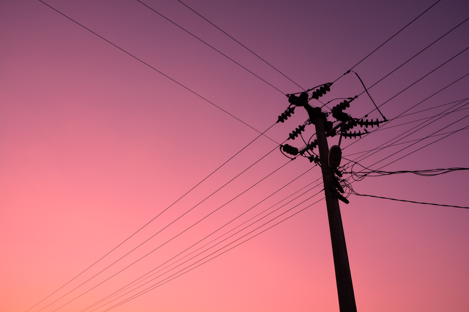 Zdjęcie przedstawia słup wysokiego napięcia na tle nieba.
