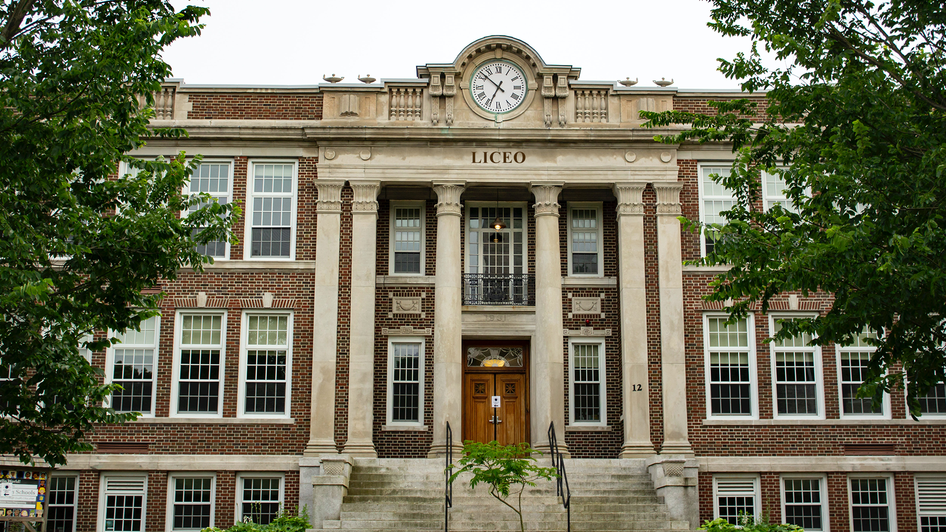 Zdjęcie przedstawia duży, trzypiętrowy budynek włoskiego liceum. Budynek ma wysokie okna, a jego front podparty  jest na kilku kolumnach. Nad wejściem znajduje się napis Liceo, a nad nim duży, okrągły zegar.