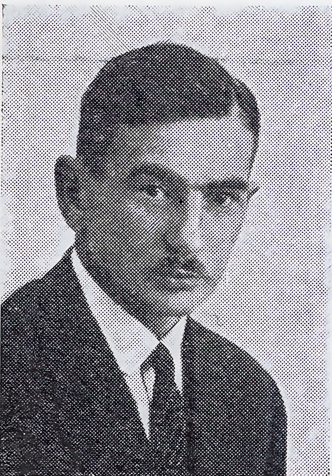 Zdjęcie Bogdana Chełmickiego. Czarno‑białe zdjęcie. Mężczyzna  o ciemnych, zaczesanych na bok włosach, z wąsem, w garniturze.