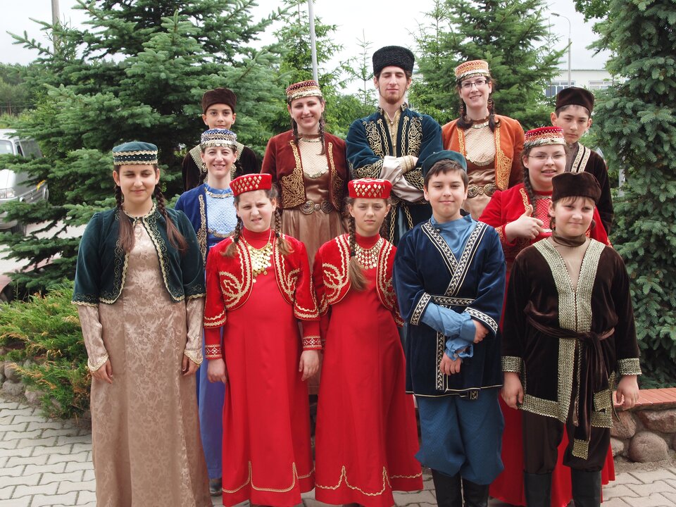 Ilustracja przedstawia karaimską młodzież w tradycyjnych strojach Karaimów, stroje miały wschodni styl. Strój żeński składał się z koszuli, długiej do pięt sukni, sięgającej talii krótkiej bluzeczki z szerokimi, rękawami niżej łokcia, oraz wierzchniego kaftana. Strój męski składał się ze spodni, 2 koszul, długiego, prążkowanego kaftana z prostym kołnierzykiem, oraz klamrami na piersi od szyi do tali. Talię Karaimi obwiązywali plecionym pasem. Na kaftan nakładali narzutkę z rękawami lekko poniżej łokcia.