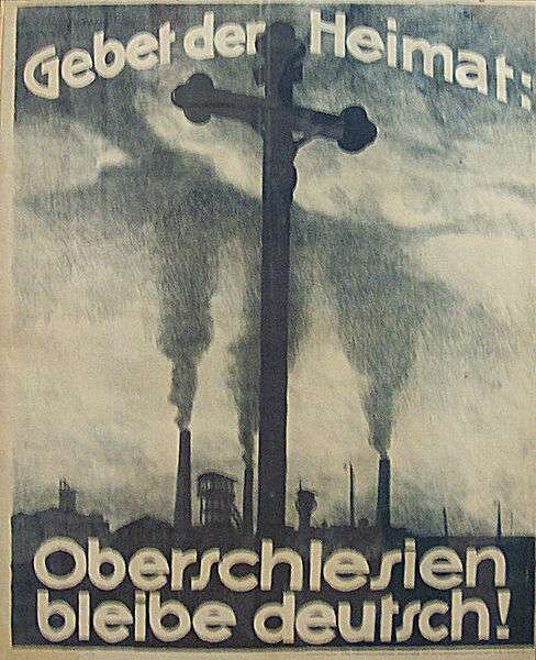 Plakat przedstawia krzyż z  figurą ukrzyżowanego Chrystusa. W tle kominy fabryk. Od góry napis głosi: Modlitwa za ojczyznę: Górny Śląsk pozostanie niemiecki. 