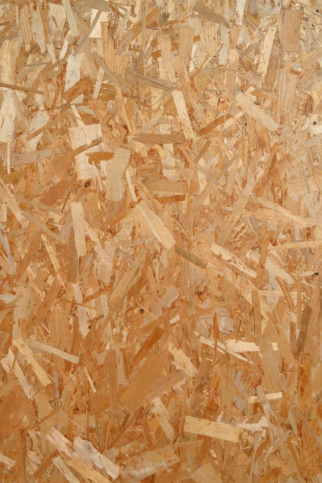 Zdjęcie przedstawia zbliżenie na płytę wiórową o gładkiej, ale nierównomiernej strukturze składającej się z wielu odcieni drewna i wielu faktur.