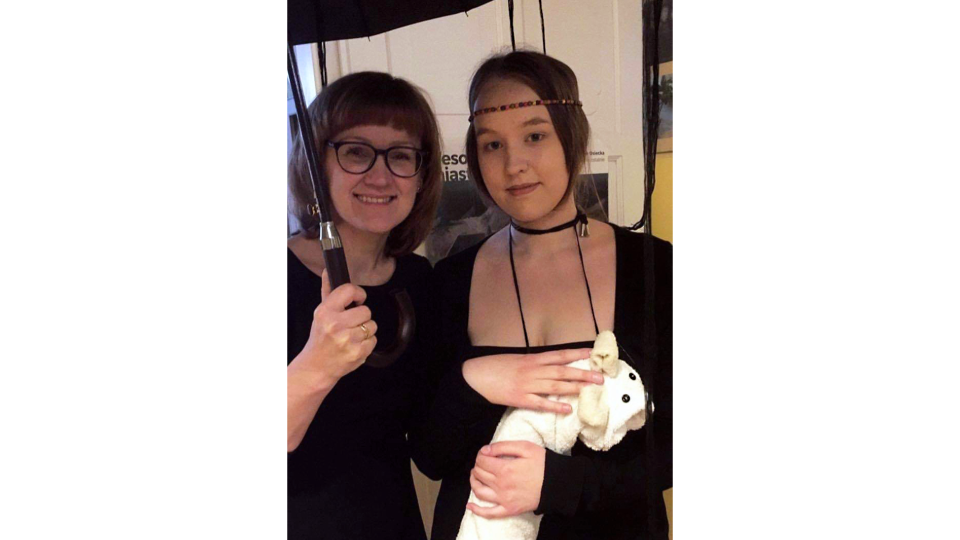  Zdjęcie przedstawia dwie kobiety. Kobieta po lewej stronie jest uśmiechnięta, nosi okulary, a w ręku trzyma parasol. Kobieta po prawej stronie trzyma w rękach maskotkę zwierzęcia, na głowie ma wąską opaskę z koralików. Jest ucharakteryzowana na postać z obrazu "Dama z gronostajem".