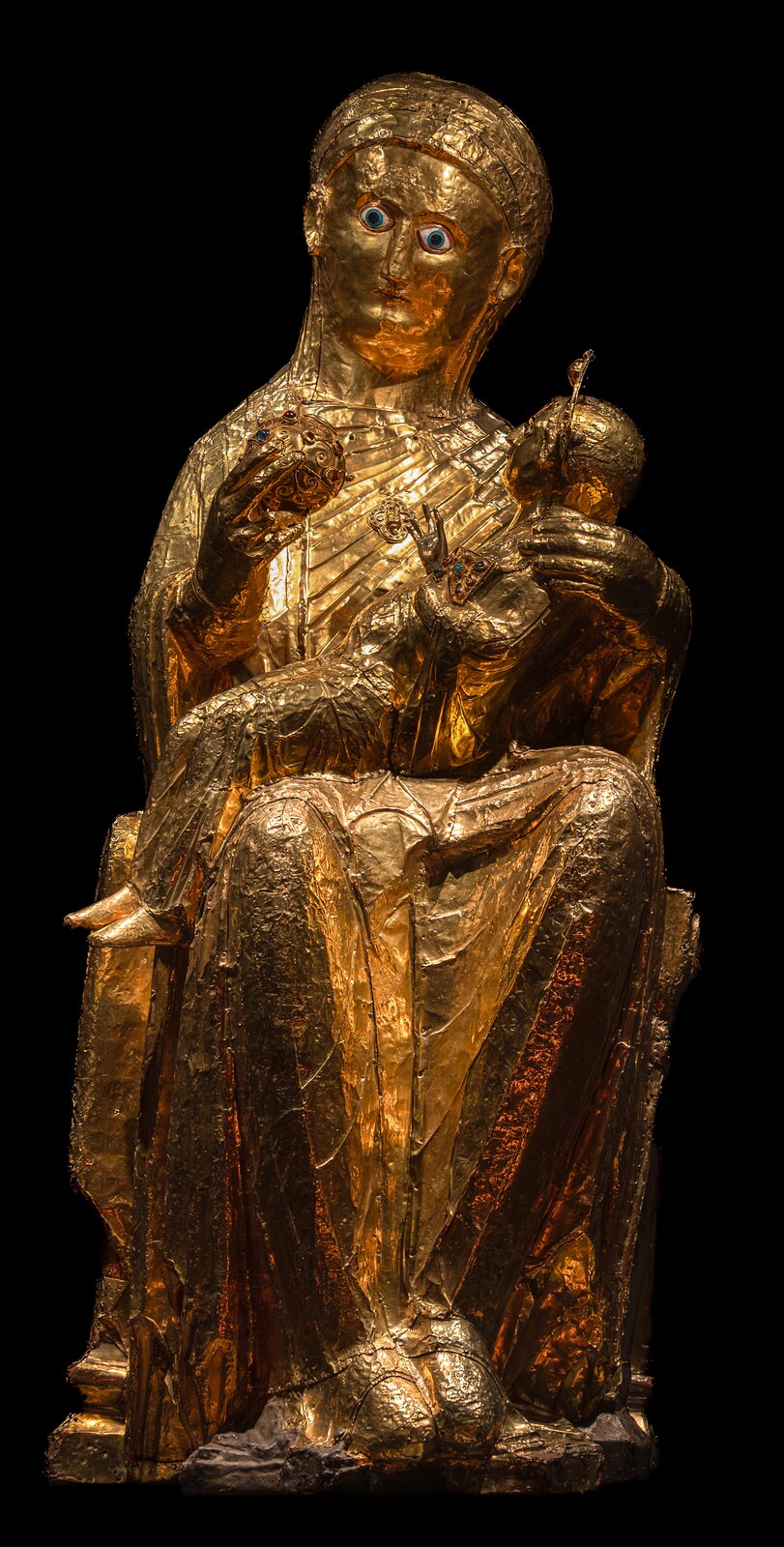 lustracja przedstawia zdjęcie rzeźby „Madonna z Essen”, która w całości jest pokryta złotem. Madonna siedzi na tronie i trzyma Jezusa na swoich kolanach. Dzieciątko siedzi bokiem. W prawej dłoni Madonna trzyma kulę. Jezus ma wzrok skierowany na kulę ziemską, którą błogosławi prawą ręką. Oczy matki i dziecka wykonane są z jasnoniebieskiej i, białej emalii. Aureola dziecka, a także książka, którą trzyma w lewej ręce, części tronu i kuli są ozdobione emaliami, kamieniami szlachetnymi i filigranem.