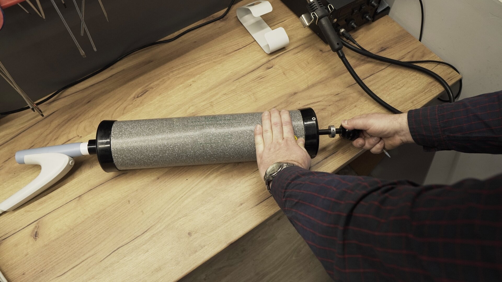 Na zdjęciu technik cewą ręką przytrzymuje tubę pompy, druga znajduje się na rękojeści wsuniętego tłoka.
