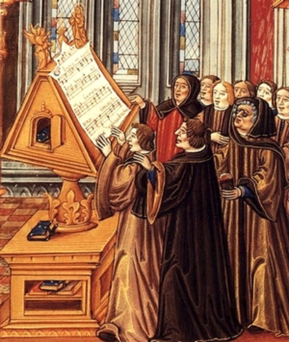 Fotografia przedstawia Johannes Ockeghem dyrygującego chórem wykonującym Glorię. Na zdjęciu znajduje się dziewięciu mężczyzn, którzy ubrani są w długie brązowe szaty. Przed nimi znajduje się drewniany stojak z nutami.