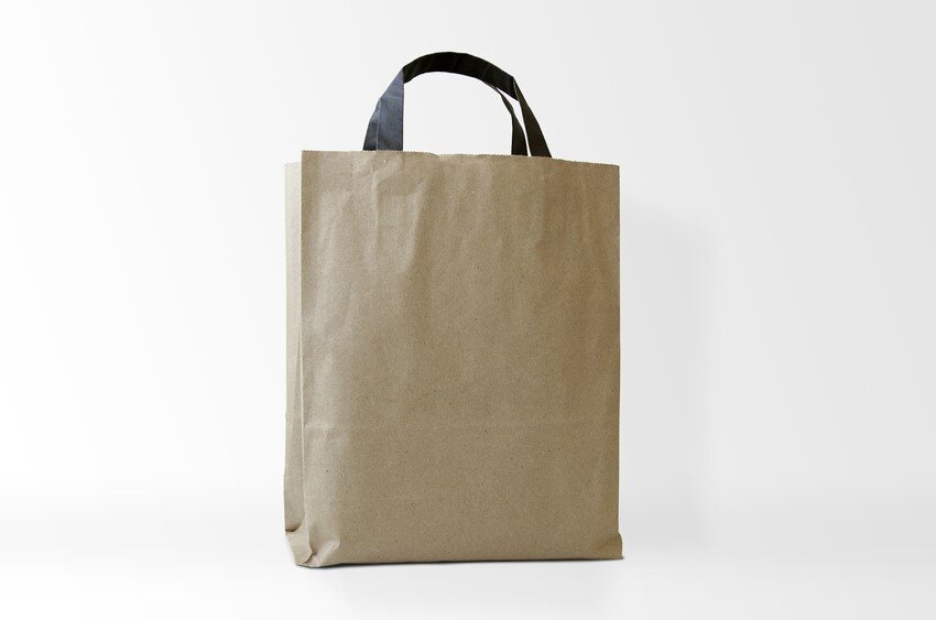 Zdjęcie przedstawia jasnobrązową torbę papierową bez nadruku o czarnych uszach.