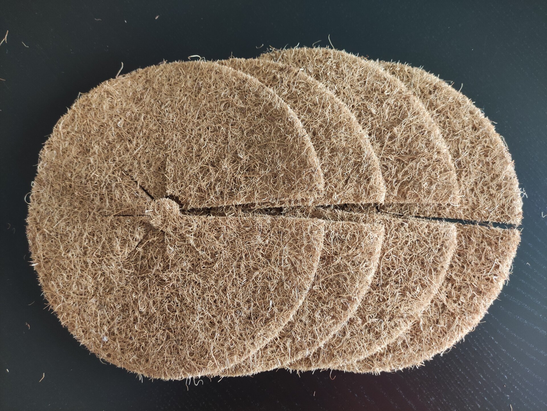 Na zdjęciu widoczne cztery krążki z włókna kokosowego ułożone jeden na drugim. Każdy krążek ma rozcięcie, biegnące od środka do boku.