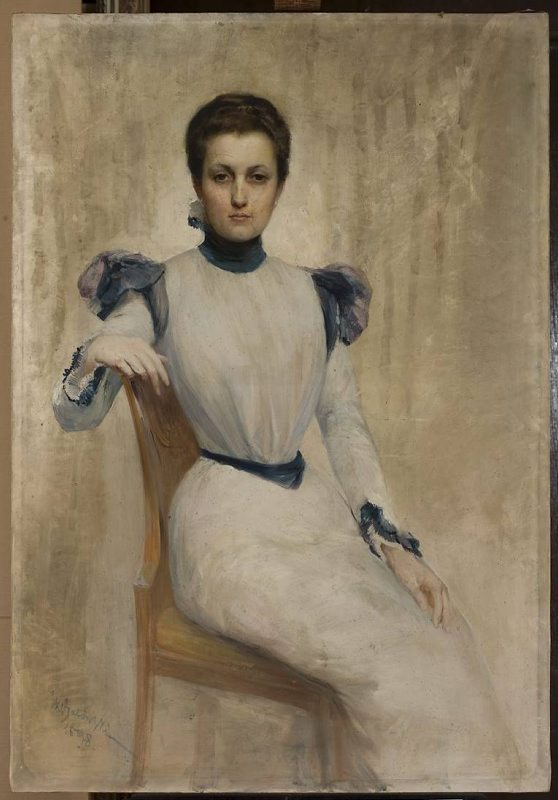 Obraz przedstawia portret młodej kobiety. Jej twarz jest pociągła, nos spiczasty, usta wąskie. Kobieta ma duże, brązowe oczy i ciemne, spięte włosy. Ubrana jest w sukienkę sięgającą kostek, ze stójką. Siedzi na krześle.