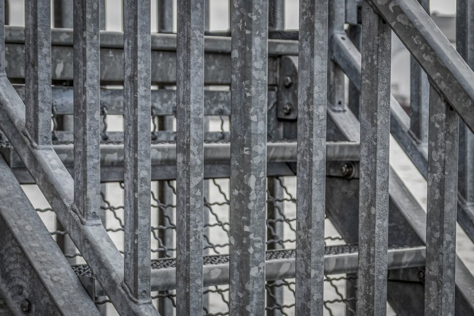 Zdjęcie przedstawia metalowe schody i balustradę z białym nalotem.