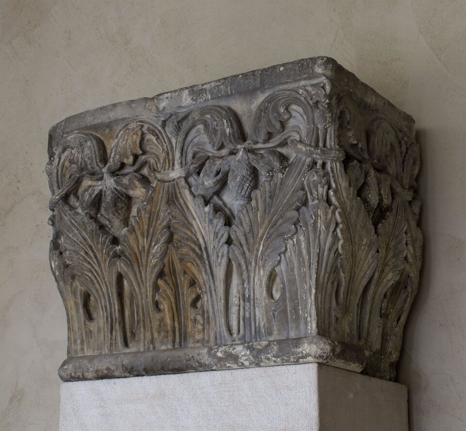 Ilustracja przedstawia głowicę kolumny, zdobioną akantem. Całą kostkową głowicę dekorują zwinięte liście.