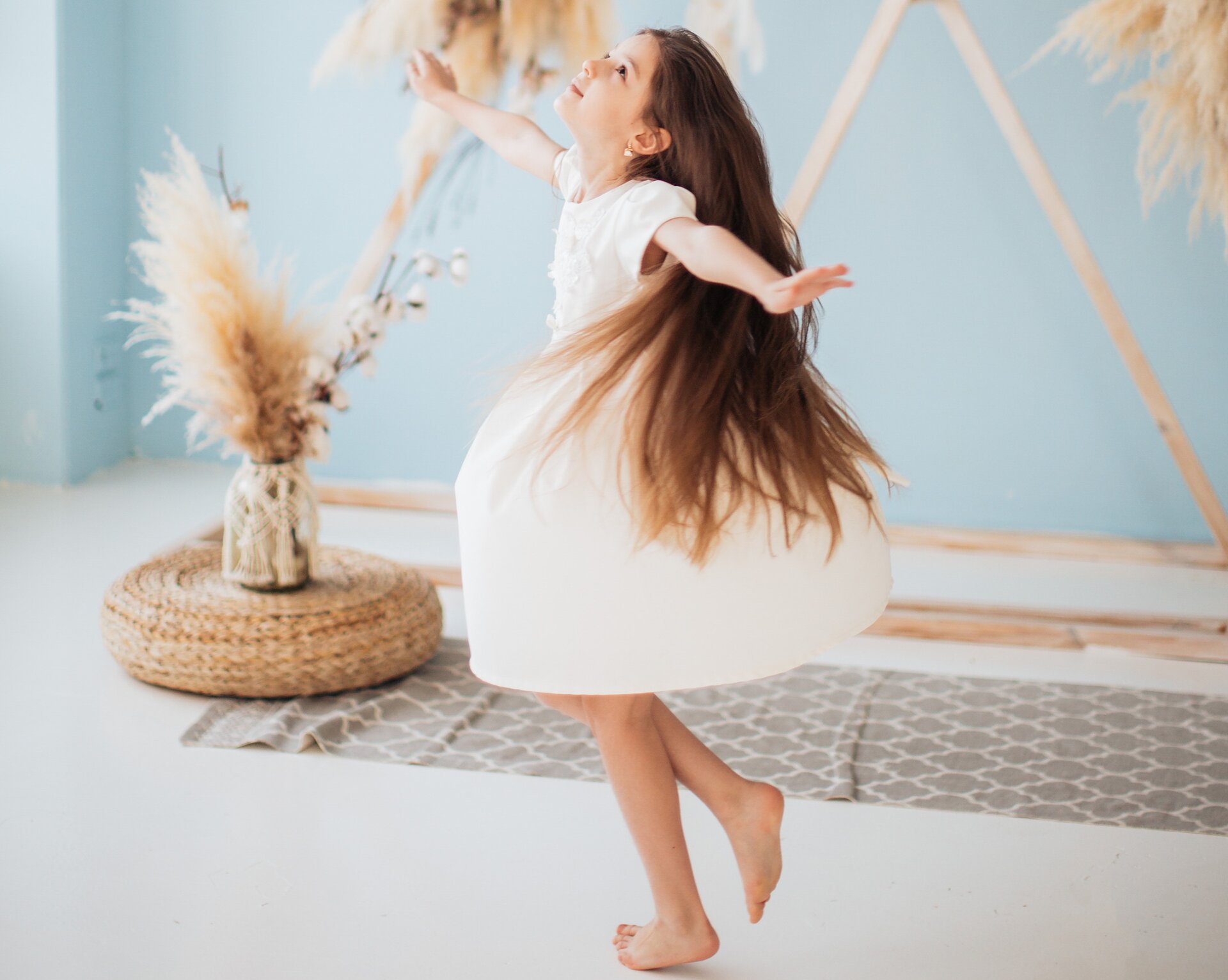 Zdjęcie przedstawia tańczącą dziewczynkę w jasnej sukience.