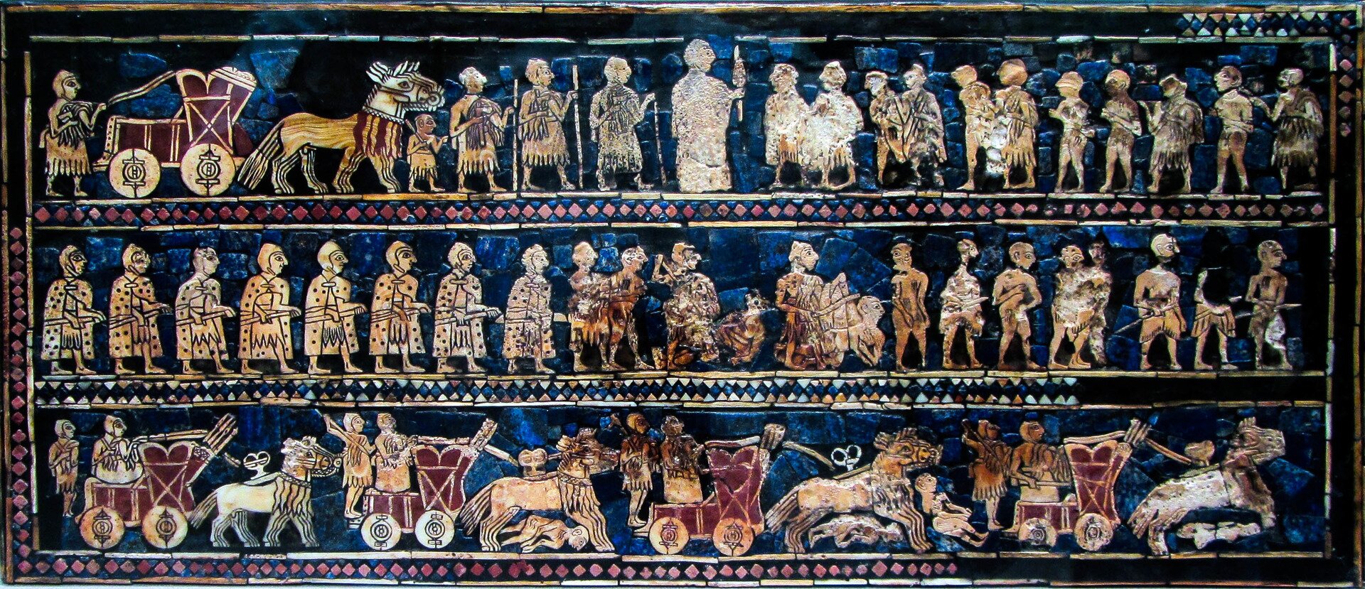 Fotografia płaskorzeźby przedstawiająca Sumerów podczas wojny w okresie starożytności. Widoczni są żołnierze z włóczniami i bojowe rydwany.
