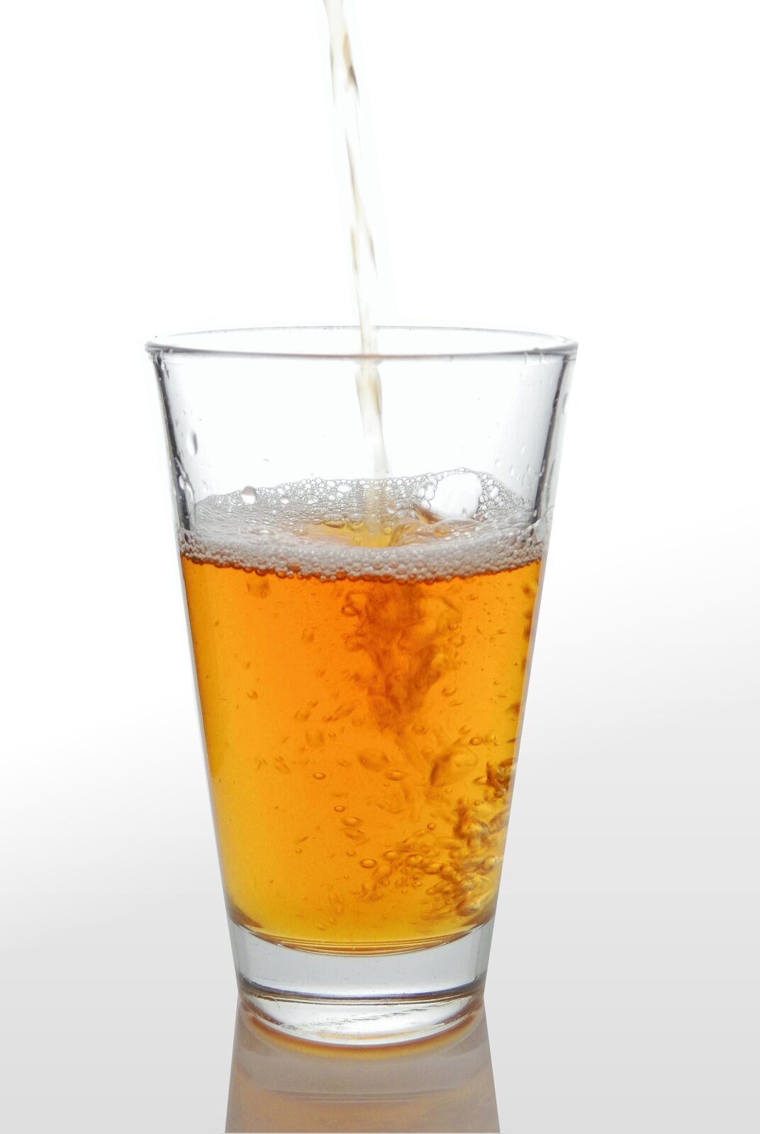 Fotografia ukazuje jasno pomarańczowy sok w szklance.