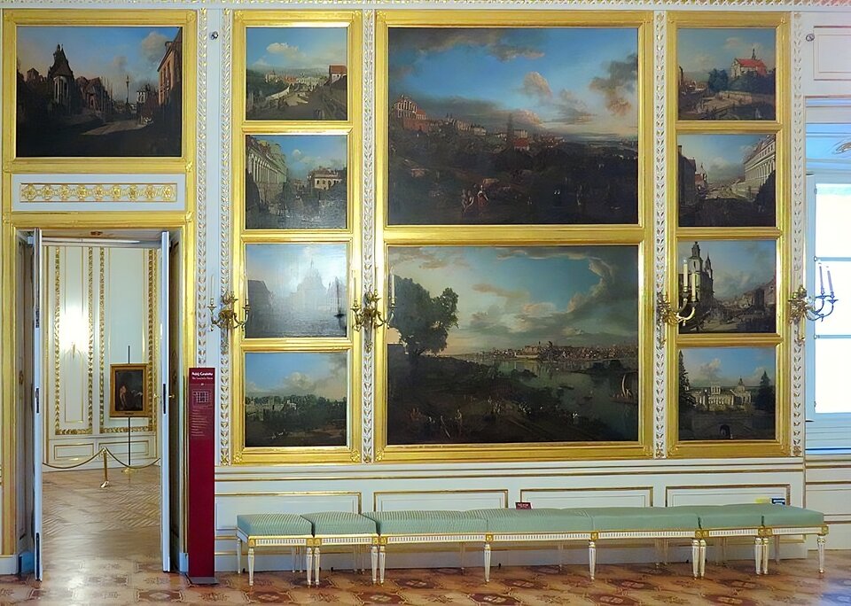 Zdjęcie przedstawia ścianę Sali Canaletta z wedutami Bernarda Bellotto Canaletta. Nad drzwiami znajdującymi się po lewej stronie jest widoczny obraz „Widok kościoła Bernardynek i kolumny Zygmunta III od strony zjazdu do Wisły”. Na prawo od niego wiszą: od góry w dół- „Pałac Błękitny”, „Ulica Miodowa”, „Kościół Sakramentek” i „Pałac w Wilanowie od strony południowej”. Na prawo od nich jest „Widok Warszawy z Pałacem Ordynackim”, a pod nim „Widok Warszawy od strony Pragi”. Na prawo od tych obrazów jest: od góry w dół- „Kościół Reformatów”, „Ulica Długa”, „Kościół św. Krzyża” i „Pałac w Wilanowie od strony ogrodu”. Obrazy umieszczone są w złotych ramach, między rzędami obrazów umieszczone są kandelabry. Białe ściany sali ozdabiają dodatkowo złocone ornamenty.