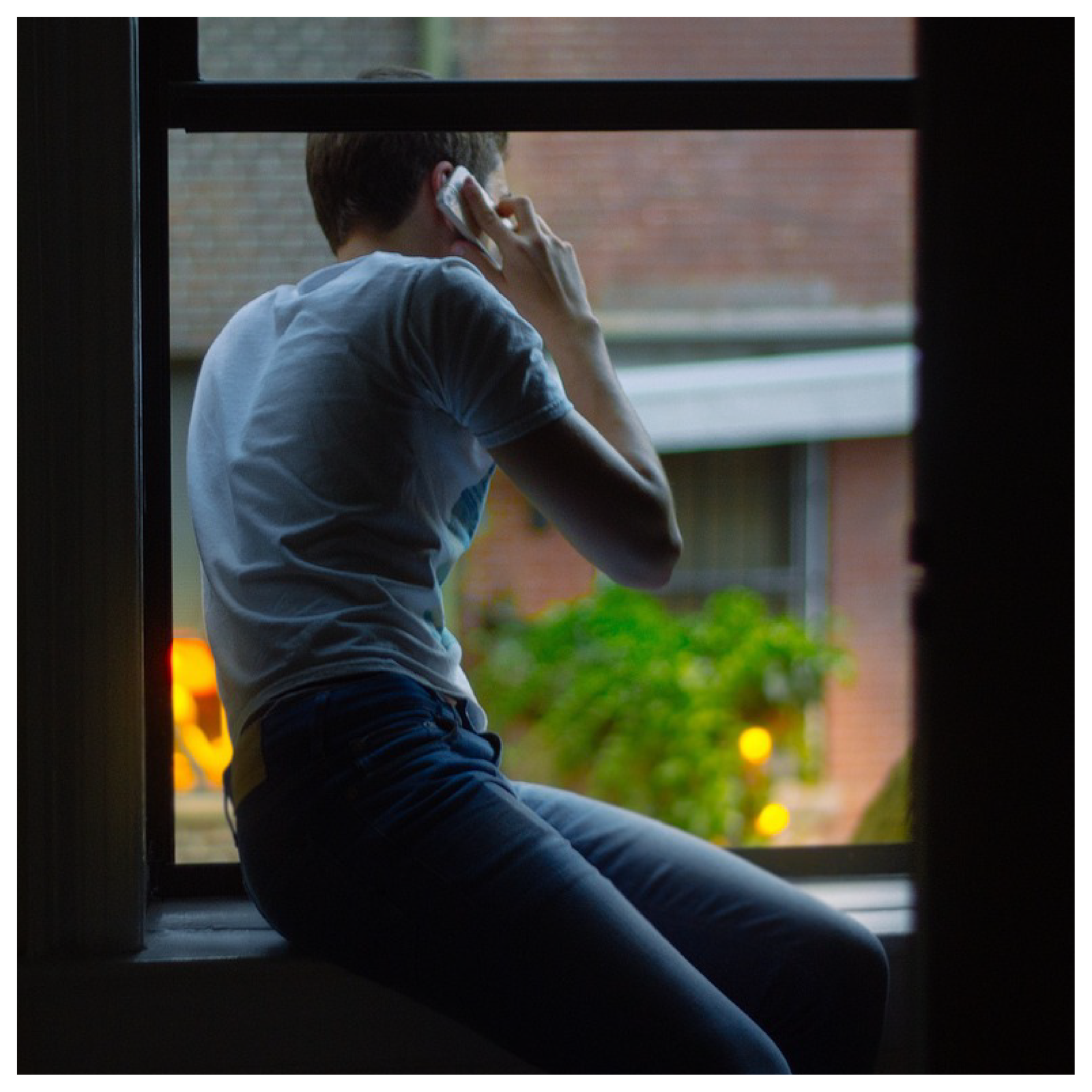 Ilustracja przedstawia chłopaka w oknie, który rozmawia przez telefon.