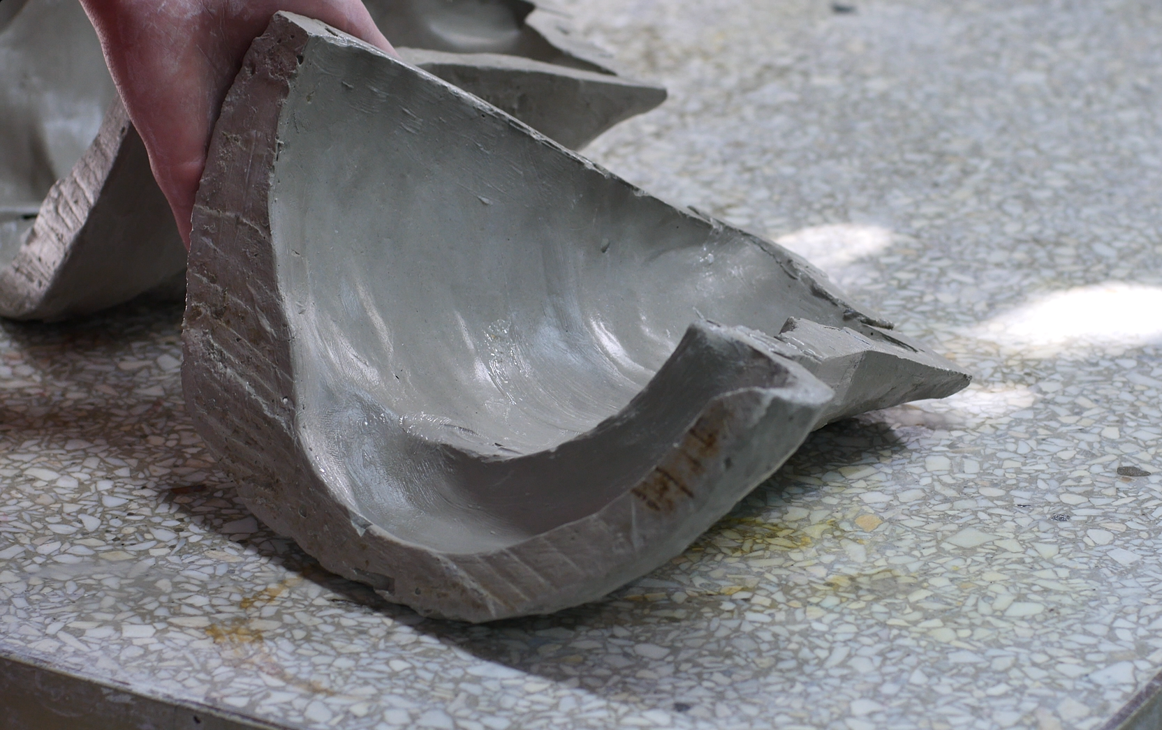 Zdjęcie przedstawia formę straconą o nieregularnym kształcie. Dwie połówki pustej formy leżą na kamiennym blacie.