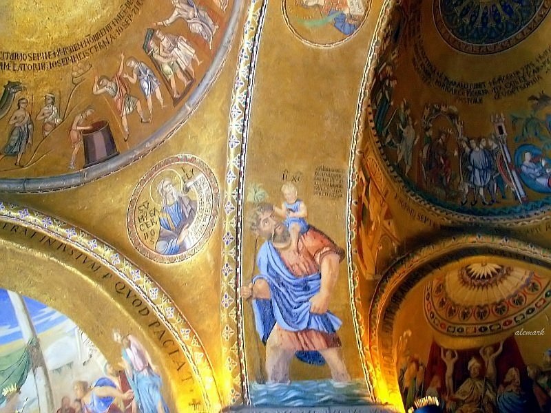 Zdjęcie ukazuje dekorację malarską na sklepieniu Bazyliki św. Marka w Wenecji. Malarstwo na złotym tle przedstawia sceny biblijne wzbogacone ornamentami geometrycznymi oraz inskrypcjami, które wypełniają dwie nisze i dwa wnętrza kopuł. Na łuku oddzielającym sklepienia przedstawiona została scena ze św. Krzysztofem, który z małym Jezusem na ramieniu przechodzi przez rzekę. 