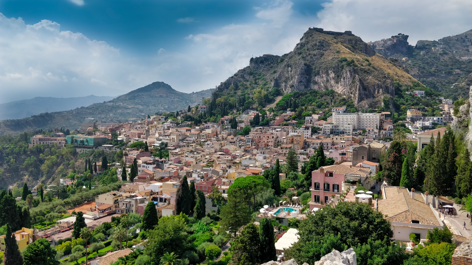 Zdjęcie przedstawia widok na włoskie miasto. W tle widoczne są góry.