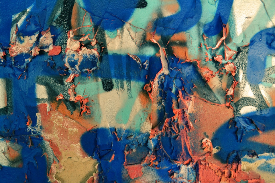 Ilustracja jest zdjęciem plam w różnych kolorach (dominują: niebieski, jasna zieleń i pomarańcz), namalowanych za pomocą spraya i pędzlem. 