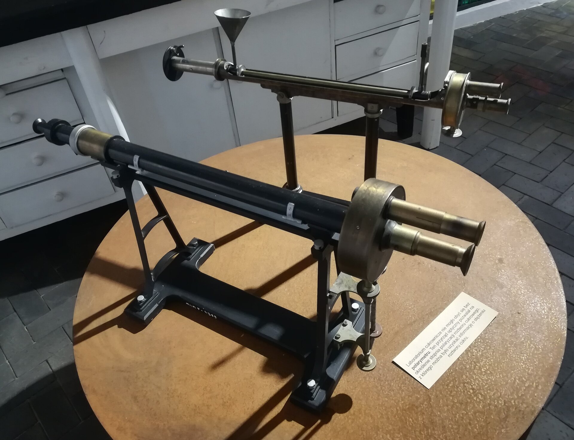 Zdjęcie przedstawiające sacharymetr pochodzący z Muzeum Narodowego Rolnictwa w Szreniawie. Urządzenie bazuje na polarymetrze, który umożliwia pomiar skręcalności. Zbudowane jest między innymi z kilku rurek, które zakończone są szklanymi soczewkami, umożliwiającymi przechodzenie wiązki światła przez badany roztwór.