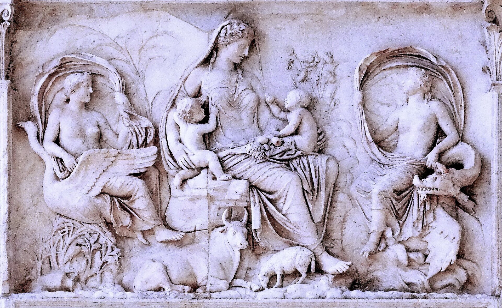 Relief zdobiący Ara Pacis przedstawia kobietę piastującą dwóch chłopców. Po jej bokach znajdują się dwie inne osoby. Wokół niej znajdują się personifikacje żywiołów oraz obraz natury: owoce (na kolanach kobiety), kwiaty, kłosy, wół i owca.