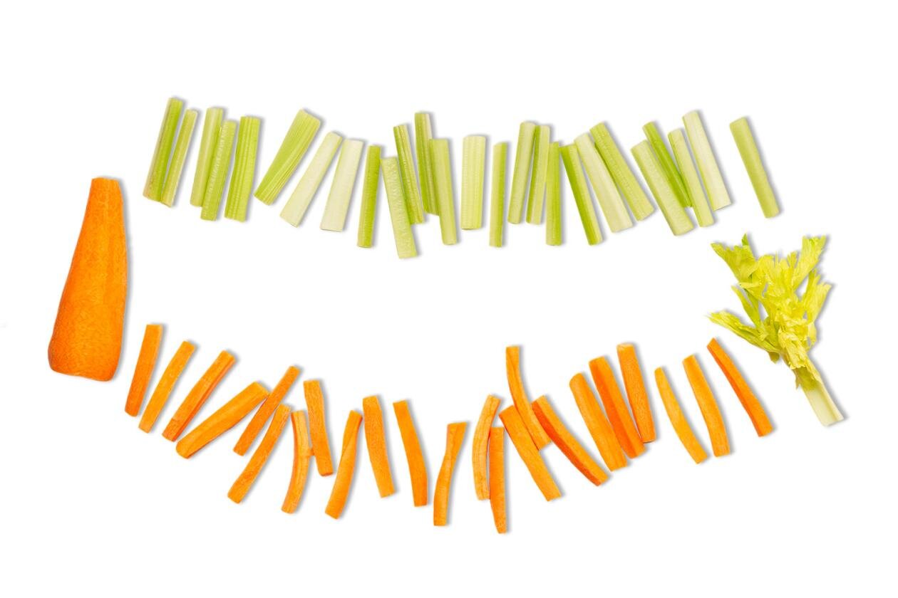 Zdjęcie przedstawia marchew i seler naciowy pokrojone techniką bátonnet. Na białym tle widoczne są u dołu obrana marchew i rząd słupków marchwi, zaś u góry rząd słupków selera naciowego i fragment selera naciowego.