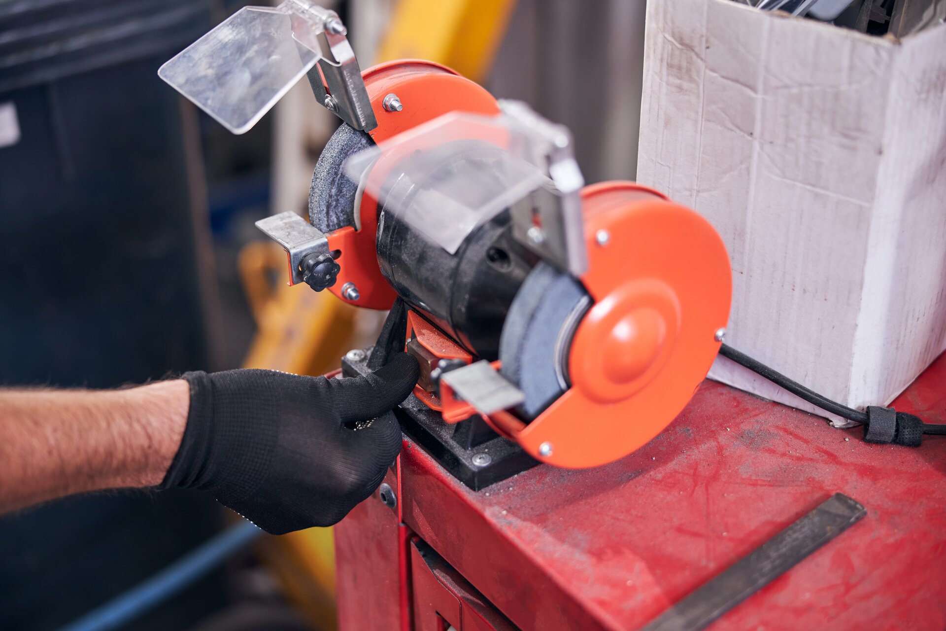 Ilustracja przedstawia niewielki walec z osłoną, przymocowany do stołu. Wewnątrz walca widoczne okrągłe tarcze o różnej średnicy i pokryte różnej grubości materiałem ściernym.